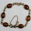 Front surface of a gold toned metal bracelet from the Sarah Coventry Pty. Ltd. jewellery range with small brown oval faux stones.