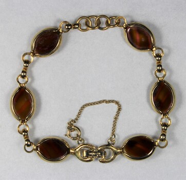 Back surface of a gold toned metal bracelet from the Sarah Coventry Pty. Ltd. jewellery range with small brown oval faux stones
