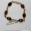 Gold toned metal bracelet from the Sarah Coventry Pty. Ltd. jewellery range with small brown oval faux stones and a 5 cm black and white scale.