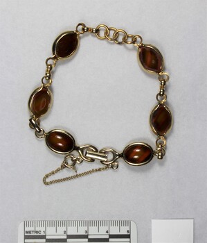 Gold toned metal bracelet from the Sarah Coventry Pty. Ltd. jewellery range with small brown oval faux stones and a 5 cm black and white scale.