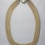 Back of a necklace  with three strands of faux pearls and a large faux pearl at the clasp.