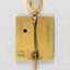 Back of a Sarah Coventry gold metal pin for five years service, with the back of a pink stone inlay and a makers stamp on the proper left side.