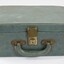 Front of a green suitcase with a handle and a metal lock for a Sarah Coventry jewellery demonstration kit.