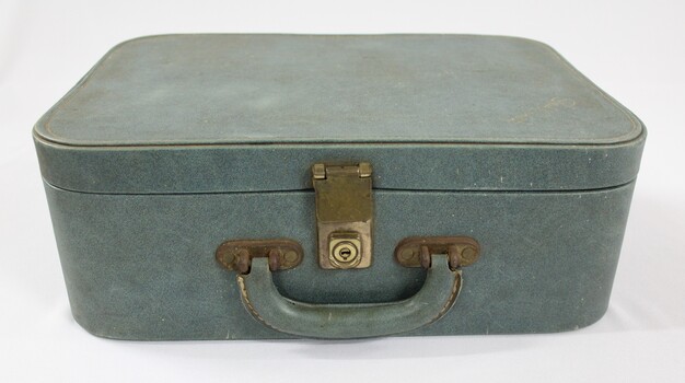 Front of a green suitcase with a handle and a metal lock for a Sarah Coventry jewellery demonstration kit.