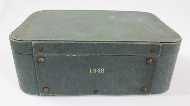 Back of a green suitcase for a Sarah Coventry jewellery demonstration kit with "1348" printed in gold.