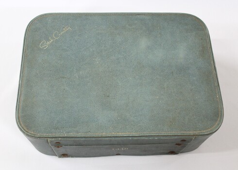 Top surface of a green suitcase for a Sarah Coventry jewellery kit with the name Sarah Coventry in gold lower case letters.