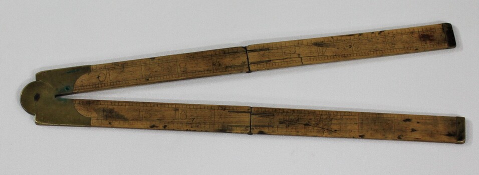 Wooden fold out carpenter ruler with bendable brass hinges and imperial measurements engraved into the wood. 
