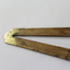 Wooden fold out carpenter ruler with bendable brass hinges and imperial measurements engraved into the wood, detail of brass hinge.