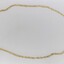 Gold toned metal chain in a side-on view.