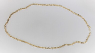 Gold toned metal chain in a side-on view.