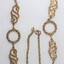 Detail of the two circular elements and two swirling decorative elements, as well as the clasp and small rhombus-shaped attachment near the clasp.