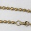 Detail of a gold toned beaded metal chain from the Sarah Coventry jewellery range, showing the clasp with the Sarah Coventry mark stamped on it.