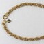 Deail of the gold toned metal rope chain from the Sarah Coventry jewellery range, with a small rhombus-shaped attachment at the clasp. 
