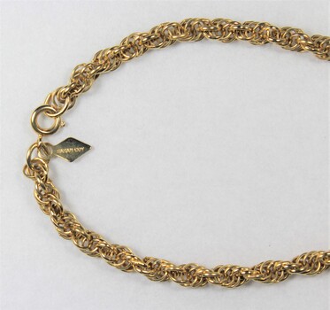 Deail of the gold toned metal rope chain from the Sarah Coventry jewellery range, with a small rhombus-shaped attachment at the clasp. 