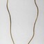 Back of a gold toned metal necklace with an oval-shaped pendant inlaid with a brown resinous material.