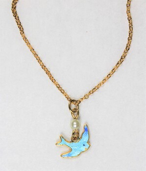 Detail of the front of the gold toned metal necklace with a small blue bird pendant and a small faux pearl. 