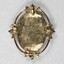 Back of a gold toned metal brooch-pendant with the Sarah Coventry copyright mark on the lower edge.