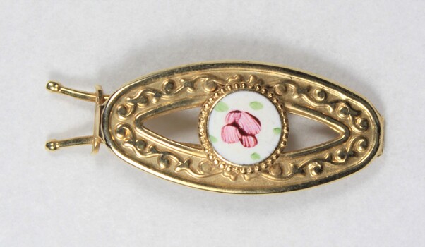 Front of a gold toned metal hair clip with a circular enamel inlay.