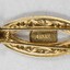 Back of a gold toned metal hair clip with a Sarah Coventry mark on the back of the circular decorative element.