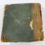 Back of a bound ledger with a deteriorated light brown leather and green textile cover.