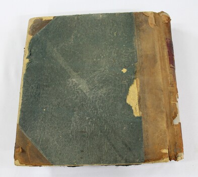 Back of a bound ledger with a deteriorated light brown leather and green textile cover.