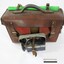 Front and top surface of a Victorian Railways guard's satchel, with a rolled up green signal flag attached behind the handle and a dark blue metal lamp attached to the front, and a black and white 10 cm scale in the foreground..