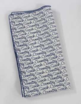 Scarf with the Sarah Coventry logo printed repeatedly in blue on a white background, folded.