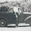 Black and white photograph of man standing beside a 1930s ute 