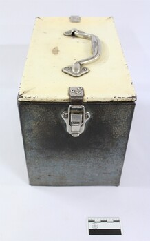 One end of a rectangular grey railways lunch box with scale.