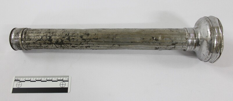 Side view of a metal torch with scale.