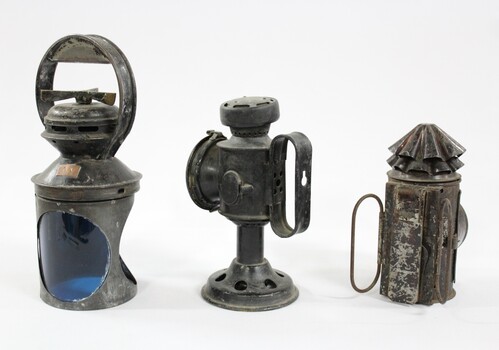 Three metal and glass lamps, one with blue filter showing, used for signalling on the Victorian Railways.