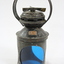 Exterior casing of a black painted metal railway signal lamp with "A y" stamped on a small copper plate on one side, as well as a circular blue glass filters and a turning mechanism on the top under a circular handle.