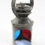 Exterior casing of a black painted metal railway signal lamp with circular blue and red glass filters and a turning mechanism on the top under a circular handle.