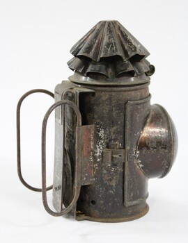 Black painted metal signal lamp with two thin elongated oval shaped handles at the back.