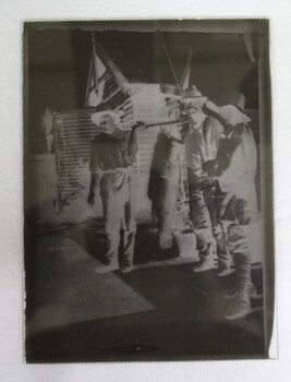 Negative transfer on glass dry plate, photograph shows three men holding a large fish 