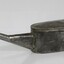 Side of a grey metal container with a long spout.