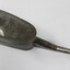 View from above of a grey metal container with a long spout, handle and a chain attached to the lid.