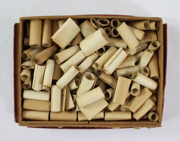 Dozens of small paper scrolls with bible verses printed on them stored inside a small cardboard box 