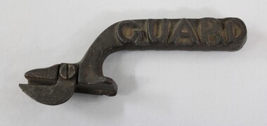 Dark brown cast iron can opener with the word 'GUARD' in raised letters on the side of the handle.