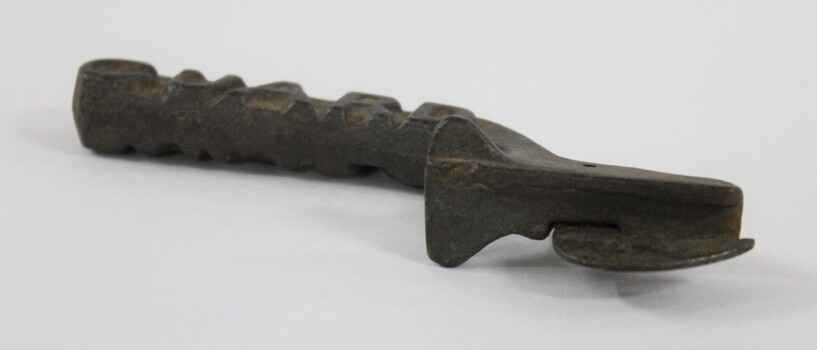 Underside of a dark brown cast iron can opener