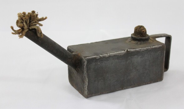 Rectangular grey metal lamp with a textile fibre wick.