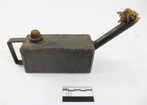 Side of a rectangular grey metal lamp with scale.
