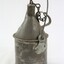 Grey metal container with a looped handle attached to the sides, as well as a handle on the back of the container with a metal chain attached to it to secure the cap for the container. 