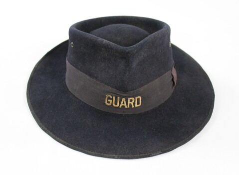 Dark blue/grey felt Victorian Railways hat with the word 'GUARD' in gold on the front of a faded brown band.