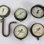 Five metal and glass water pump pressure gauges.