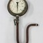 Metal and glass water pump pressure gauge with a U-shaped pipe and lever attached. Deteriorated inscription "-HOMPSONS (CASTLEMAINE)  LT-".