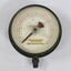 Metal and glass water pump pressure gauge, with the inscritption "No. 1609 / POUNDS PRESSURE / PER SQ. INCH / FEET HEAD OF WATER" and another inscription  hidden behind the red and black pointers.