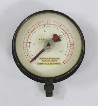 Metal and glass water pump pressure gauge, with the inscritption "No. 1609 / POUNDS PRESSURE / PER SQ. INCH / FEET HEAD OF WATER" and another inscription  hidden behind the red and black pointers.