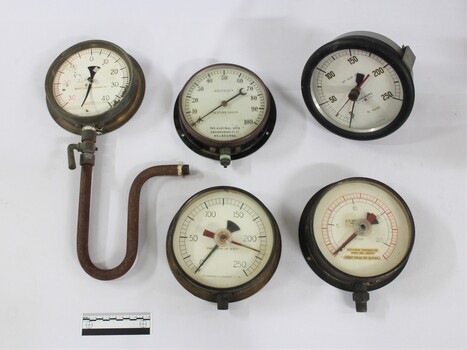 Five metal and glass water pump pressure gauges