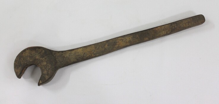 Large cast iron spanner with some red/brown rust corrosion and light brown surface dirt.